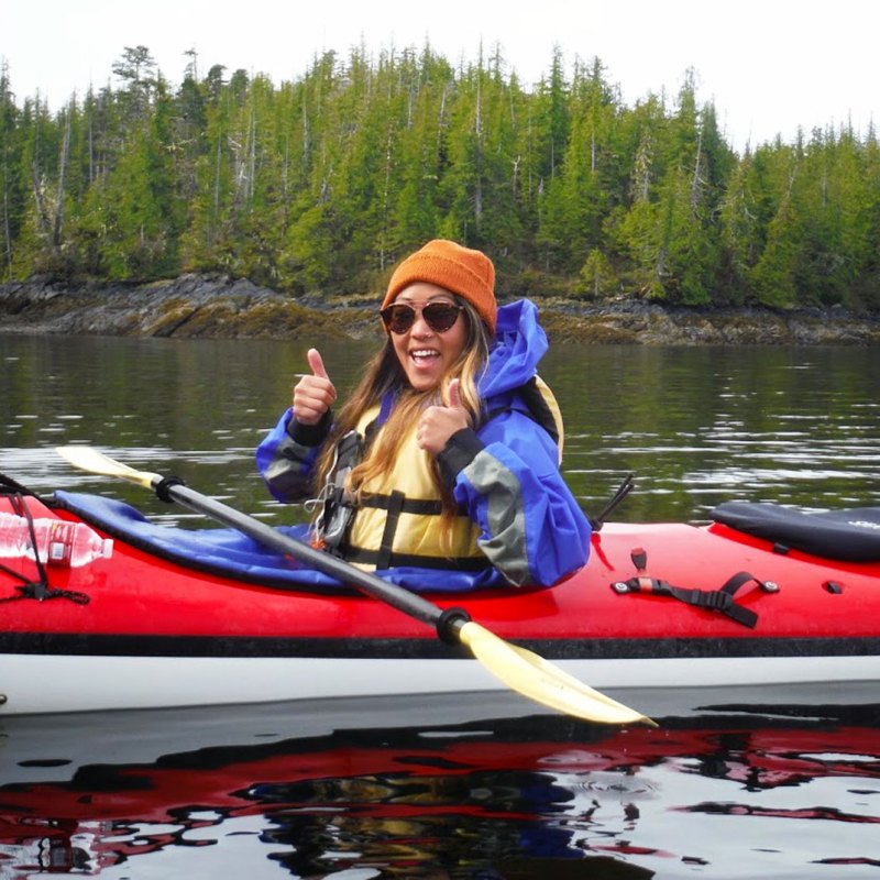 a man riding on the back of a boat next to a lake