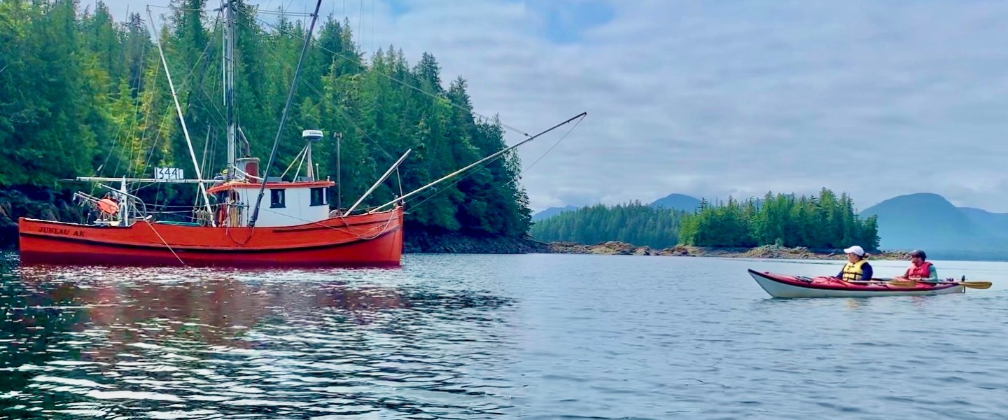 Sea Kayaking past a commercial salmon fishing boat at Orca Cove near Ketchikan, Alaska