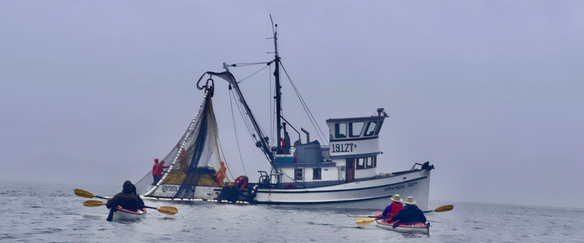 Kayaking with a salmon fishing boat at Orca Cove, Ketchikan, Alaska
